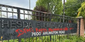 Photo of the Bethesda Elementary School marquee that reads "7600 Arlington Road" in white text. Black spray paint reads "Free Gaza now" and "Gaza is starving." Red spray paint in the center of the sign reads "Israel rapes men, women and children."