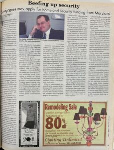 Photo of a newspaper page that reads "Beefing up security" with the sub-headline "Synagogues may apply for homeland security funding from Maryland." There is a photo on the page of a man with short brown hair and glasses in a suit resting his head on one hand and smiling at the camera.