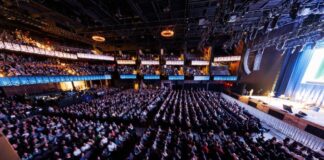 Photo of thousands of attendees seated in rows at The Anthem in D.C. The large room is dark and attendees are facing the stage.