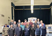 Storytelling, Community Central to Fort Belvoir Jewish Congregation’s Veterans Day Shabbat Group photo of about a dozen adults dressed in business casual attire inside a large room. The man on the far left is wearing a full military uniform.