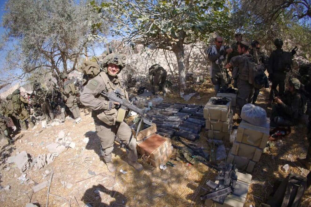 Photo of a man dressed in a military uniform posing outside with his gun.
