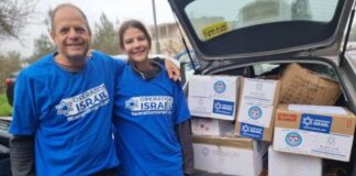 Photo of a man with his arm around a woman. They are both wearing blue T-shirts that read "Operation Israel." They are standing outside an open car trunk packed with boxes.