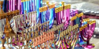 Stock photo of a bunch of metallic-colored menorahs on a table.