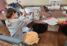 Photo of a young teen using a sewing machine on a table.