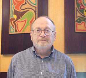 Headshot of a man with glasses smiling at the camera.