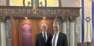 Photo of two men wearing suits standing in a synagogue.