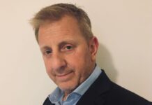 ‘Even More Robust’ Synagogue Security for High Holidays Headshot of a man with short ginger hair smiling at the camera. He is wearing a black blazer over a light blue button-down shirt.