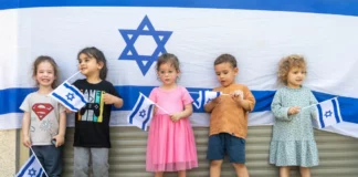 Children standing in front of an Israeli flag.