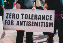 Opinion: Antisemitism Is Rising. Here’s What We Need to Do to Fight Back. The phrase " Zero tolerance for antisemitism " drawn on a carton banner in hand.