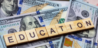 Scrabble tiles that say "education" sitting on top of money