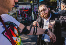 A Chabad emissary helps a man don tefillin at Tel Aviv’s Allenby Street, Jan. 20, 2017