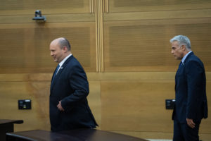 Israeli Prime Minister Naftali Bennett, left, and Foreign Minister Yair Lapid approach the podium ahead of a press conference at the Knesset to announce its disbanding, June 20, 2022.