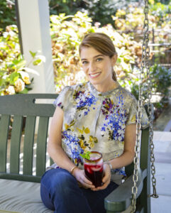 Photo of a woman with her hair pulled back in a ponytail. She's sitting on a porch swing.