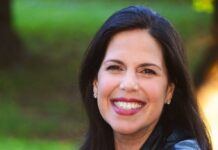 Headshot of a woman with long straight dark hair smiling at the camera.