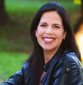 Headshot of a woman with long straight dark hair smiling at the camera.