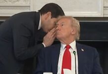 Photo of a man whispering in another man's ear.