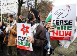 A group of people holding signs and wearing masks.