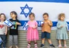 Children standing in front of an Israeli flag.