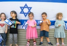 Children standing in front of an Israeli flag.