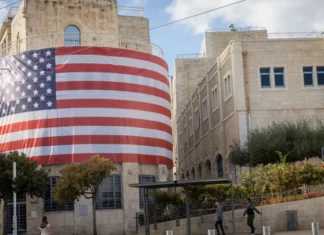 A large American flag in front of a building.