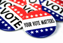 collection of election campaign vote pins on white