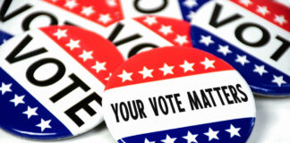 collection of election campaign vote pins on white