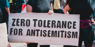 The phrase " Zero tolerance for antisemitism " drawn on a carton banner in hand.