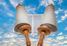 Opened Torah scrolls on the background of the sunset against the blue sky.