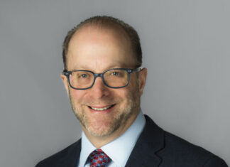 A man wearing glasses and a jacket and tie.